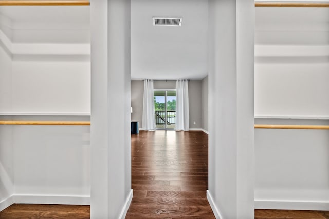corridor with wood finished floors, visible vents, and baseboards