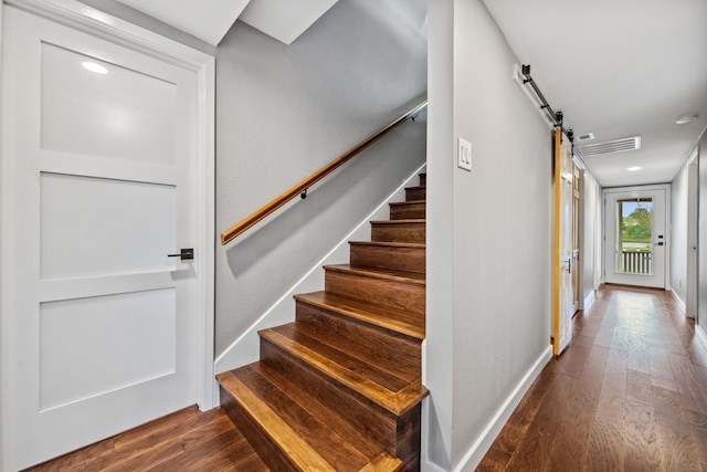 staircase featuring recessed lighting, wood finished floors, a barn door, and baseboards