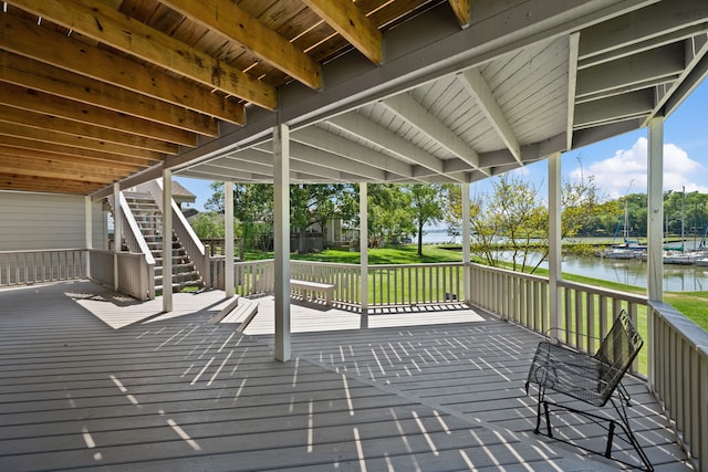 wooden terrace with stairway, a yard, and a water view
