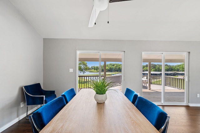 dining area featuring baseboards, wood finished floors, a ceiling fan, and a water view