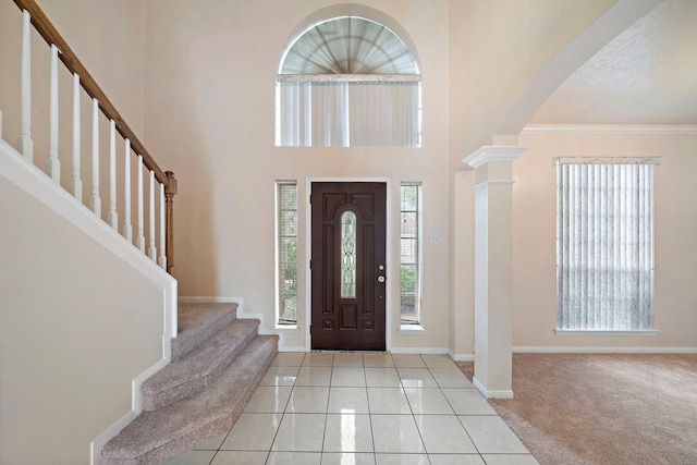 entrance foyer featuring stairs, tile patterned flooring, carpet, baseboards, and ornate columns