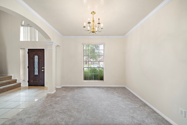 foyer featuring a chandelier, crown molding, ornate columns, arched walkways, and light colored carpet