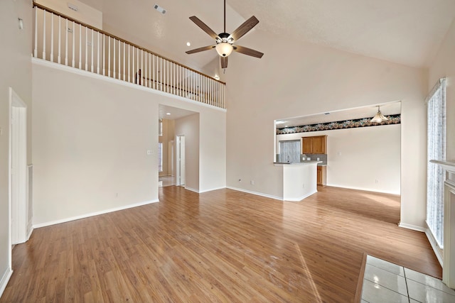 unfurnished living room featuring high vaulted ceiling, ceiling fan, light wood-type flooring, visible vents, and baseboards