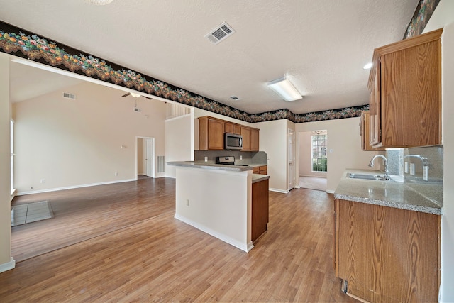 kitchen featuring stainless steel appliances, a sink, baseboards, visible vents, and open floor plan