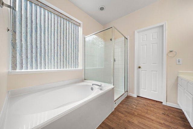 full bath featuring a shower stall, a garden tub, baseboards, wood finished floors, and vanity