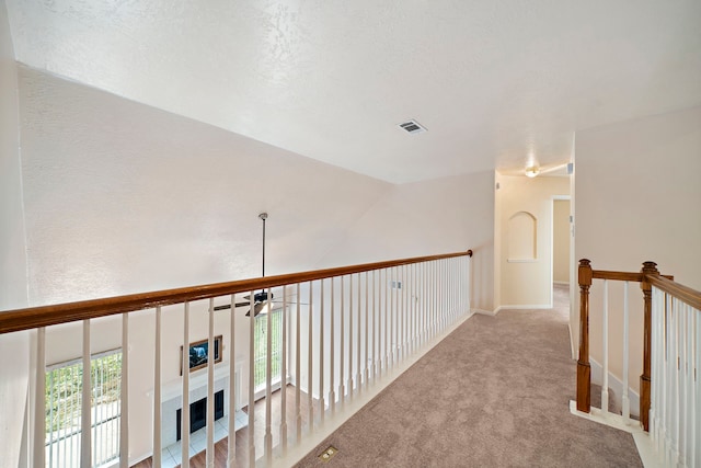 corridor featuring visible vents, a wealth of natural light, an upstairs landing, and carpet floors