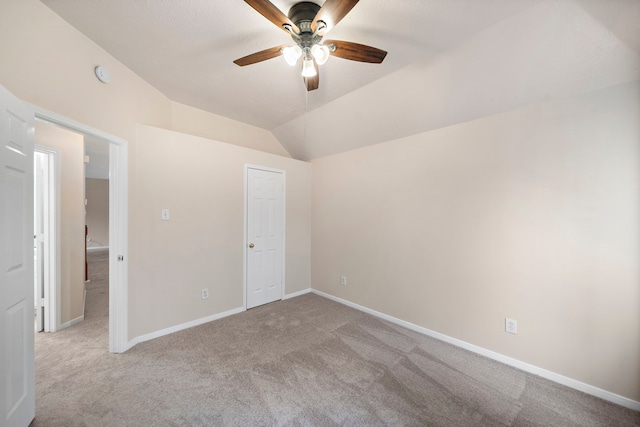 unfurnished bedroom with ceiling fan, carpet flooring, vaulted ceiling, and baseboards