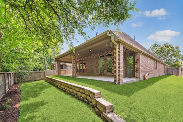 back of house featuring a lawn, a patio, a fenced backyard, and brick siding