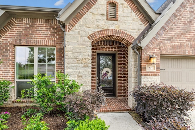 property entrance featuring brick siding, an attached garage, and stone siding