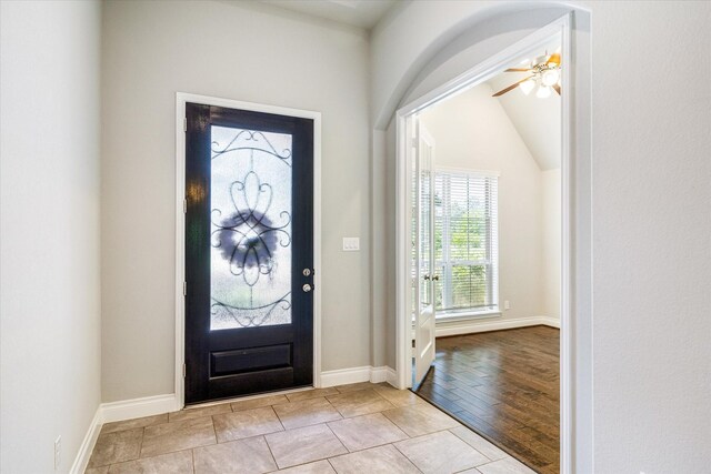 foyer with ceiling fan, vaulted ceiling, and baseboards