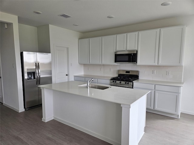 kitchen with decorative backsplash, stainless steel appliances, light wood finished floors, a sink, and visible vents