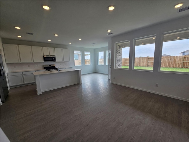 kitchen featuring baseboards, stainless steel appliances, dark wood-style floors, visible vents, and open floor plan