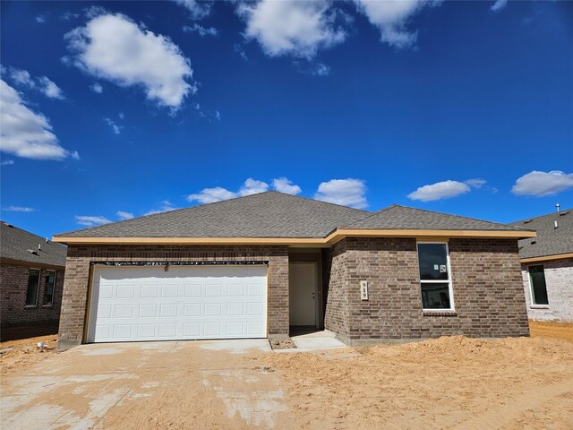 ranch-style home with driveway, a garage, and brick siding
