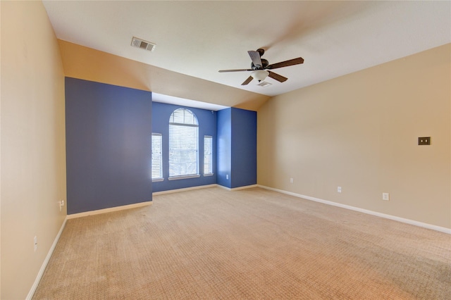 spare room with visible vents, a ceiling fan, baseboards, and light carpet