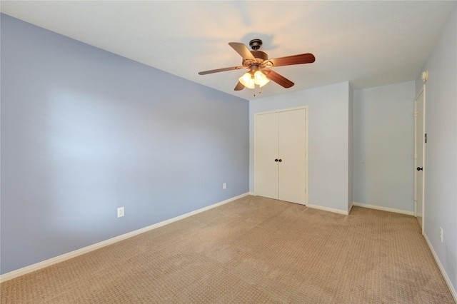unfurnished bedroom with a closet, a ceiling fan, light carpet, and baseboards