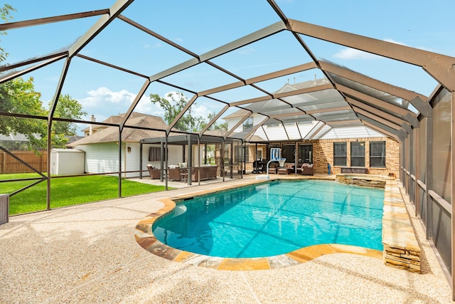 view of swimming pool with a pool with connected hot tub, a patio area, a yard, a storage unit, and glass enclosure