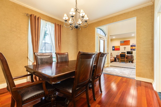 dining space with baseboards, ornamental molding, an inviting chandelier, and wood-type flooring