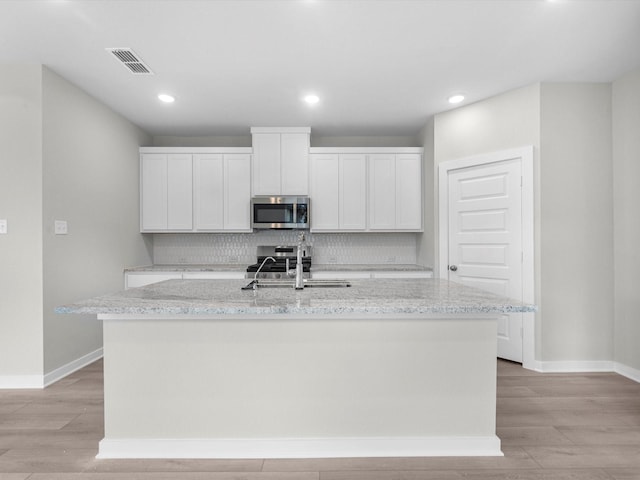 21711 White Bellflower Ln, Cypress, TX 77433 - kitchen with stainless steel appliances, backsplash, light wood finished floors, a center island with sink, and recessed lighting