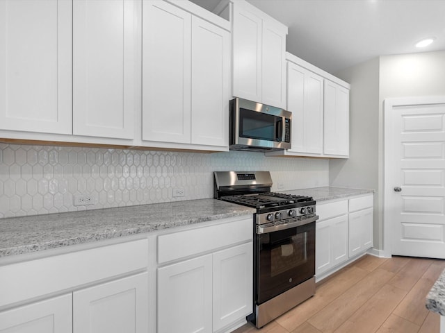 21711 White Bellflower Ln, Cypress, TX 77433 - kitchen with appliances with stainless steel finishes, white cabinetry, decorative backsplash, light wood-style floors, and recessed lighting