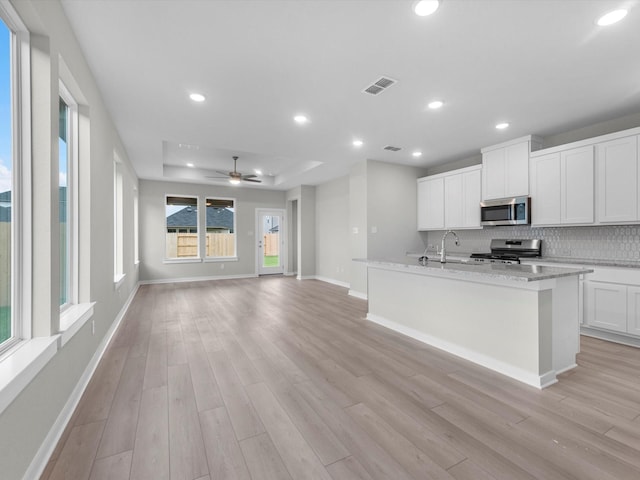 21711 White Bellflower Ln, Cypress, TX 77433 - kitchen featuring stainless steel appliances, backsplash, light wood-style flooring, a center island with sink, and recessed lighting
