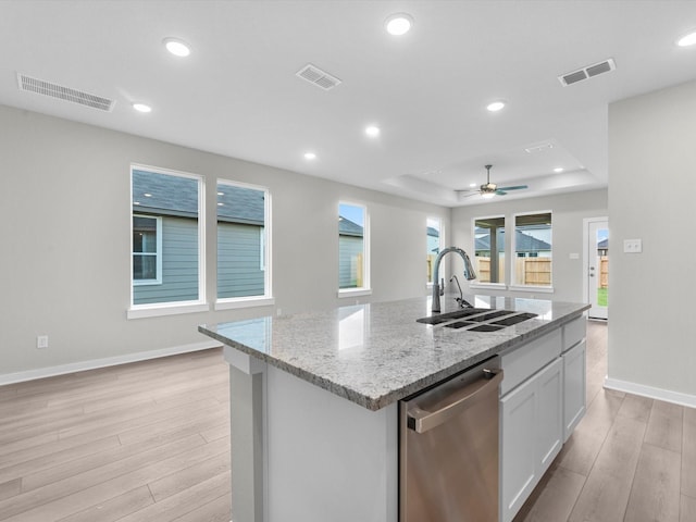 21711 White Bellflower Ln, Cypress, TX 77433 - kitchen with stainless steel dishwasher, light wood-style floors, a raised ceiling, white cabinetry, and a center island with sink
