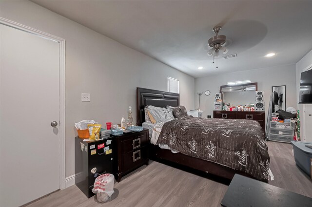 bedroom featuring wood finished floors, a ceiling fan, visible vents, and baseboards
