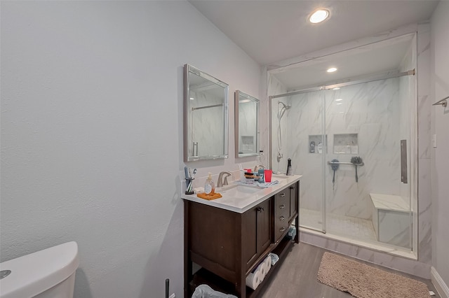 bathroom with toilet, a marble finish shower, wood finished floors, and vanity