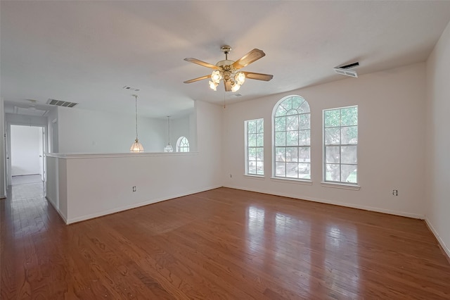 empty room with visible vents, ceiling fan, wood finished floors, and baseboards