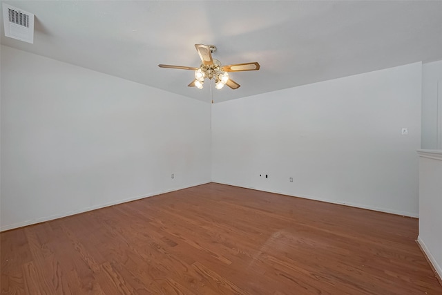 empty room featuring wood finished floors, visible vents, ceiling fan, and baseboards