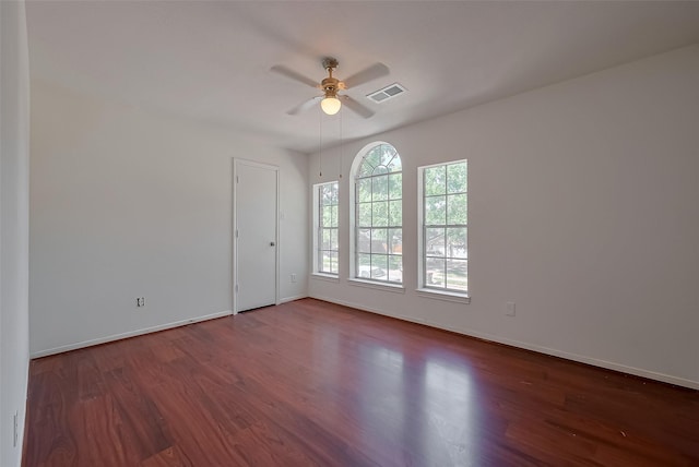 unfurnished room with baseboards, visible vents, ceiling fan, and dark wood-type flooring