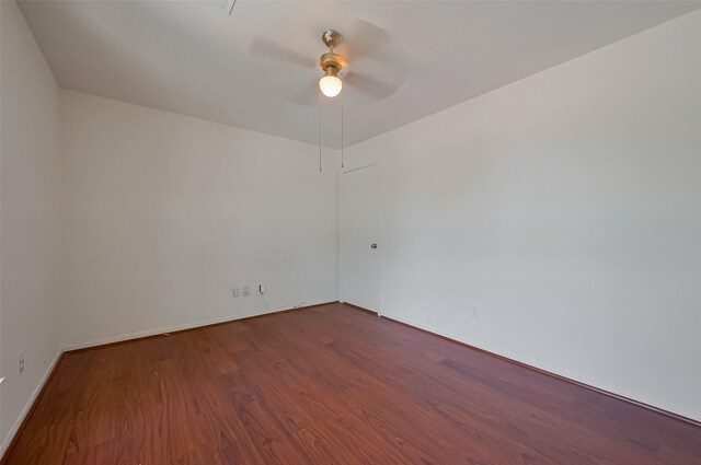 empty room with dark wood-type flooring, ceiling fan, and baseboards