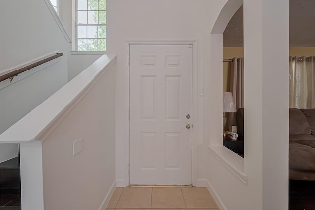 interior space with light tile patterned floors, arched walkways, and baseboards