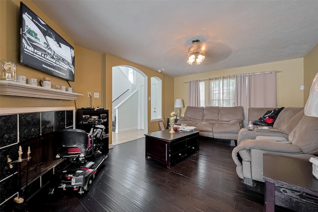 living room featuring arched walkways and dark wood finished floors