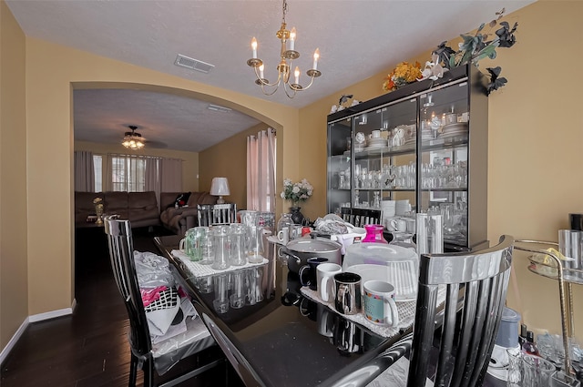 dining room with visible vents, baseboards, arched walkways, wood finished floors, and ceiling fan with notable chandelier