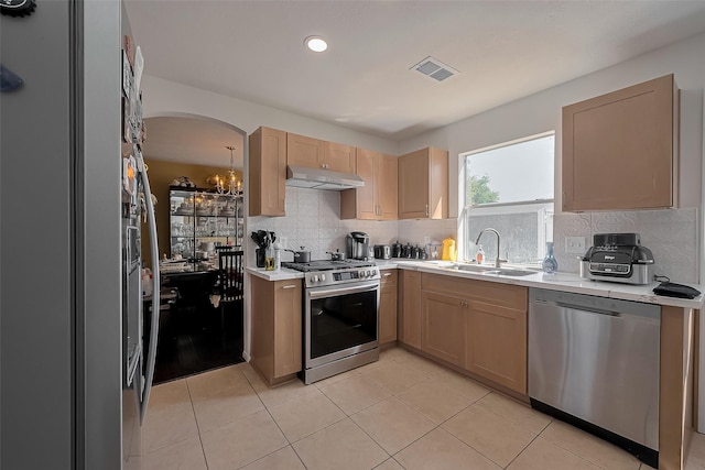 kitchen with a sink, under cabinet range hood, visible vents, light countertops, and appliances with stainless steel finishes