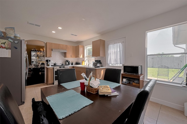 dining area with light tile patterned flooring, visible vents, plenty of natural light, and arched walkways