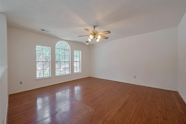 spare room with baseboards, visible vents, wood finished floors, and a ceiling fan