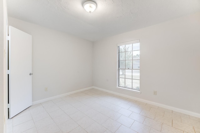 unfurnished room featuring baseboards, light tile patterned floors, and a textured ceiling