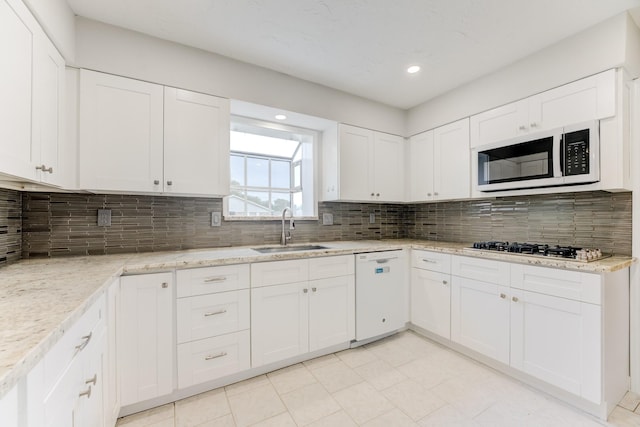 kitchen with tasteful backsplash, white cabinetry, white appliances, and a sink
