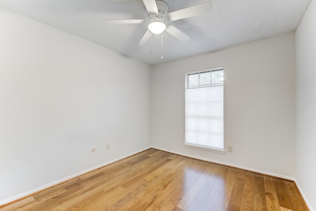 empty room with light wood-style floors, a ceiling fan, and baseboards