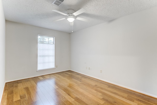 unfurnished room with a textured ceiling, visible vents, baseboards, light wood finished floors, and a ceiling fan