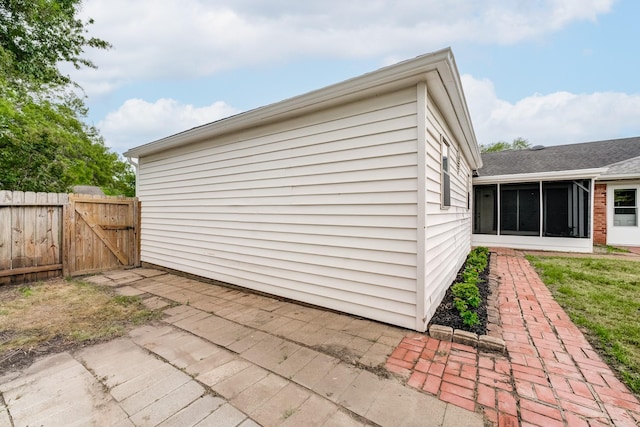 view of outdoor structure with a gate, fence, and a sunroom