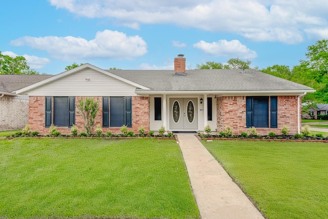 ranch-style house featuring a front lawn, a chimney, a shingled roof, and brick siding