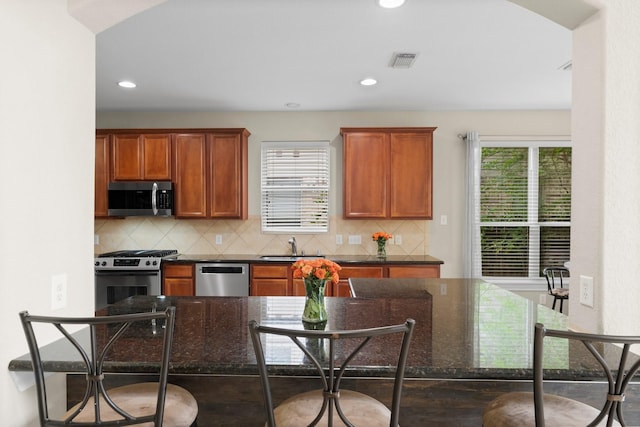 kitchen with backsplash, stainless steel appliances, a kitchen breakfast bar, and recessed lighting