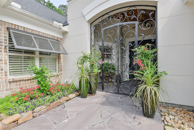doorway to property with brick siding and roof with shingles