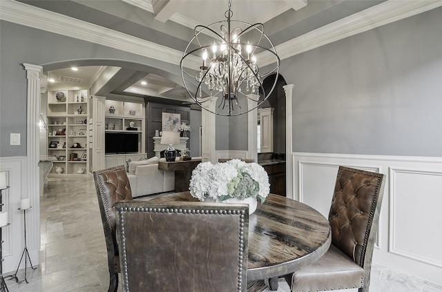 dining room featuring crown molding, an inviting chandelier, a decorative wall, arched walkways, and a wainscoted wall