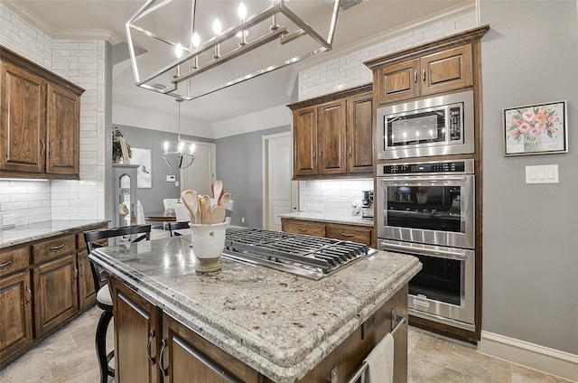 kitchen featuring a kitchen island, stainless steel appliances, an inviting chandelier, and decorative backsplash