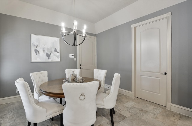 dining area with baseboards, stone finish floor, and a notable chandelier