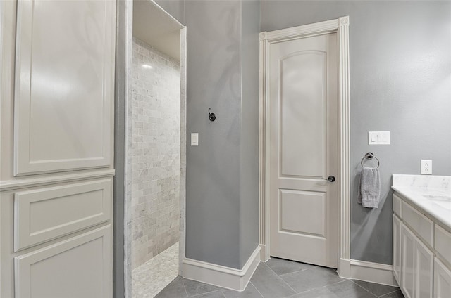 full bath featuring vanity, tile patterned floors, baseboards, and walk in shower
