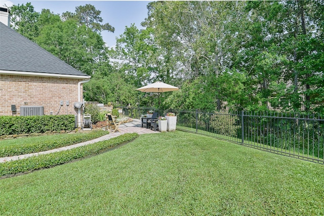 view of yard with a patio, central AC unit, and fence